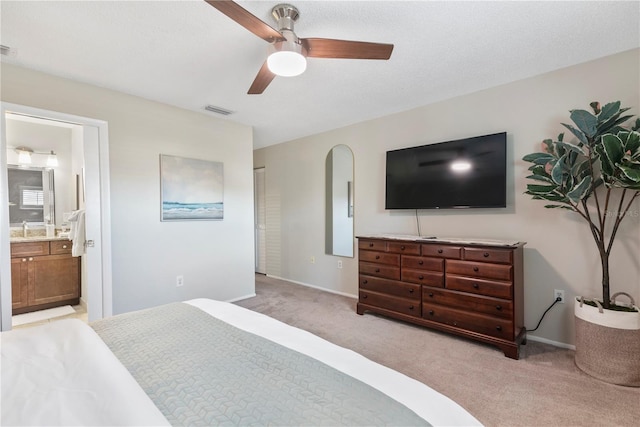 bedroom featuring light colored carpet, ensuite bathroom, a ceiling fan, a sink, and baseboards