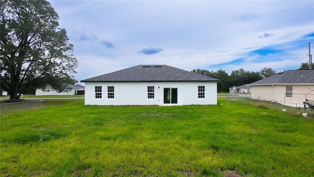 rear view of house with stucco siding and roof with shingles