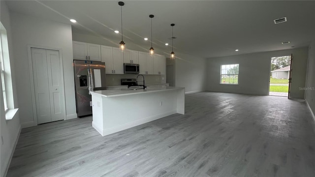 kitchen featuring stainless steel appliances, a sink, open floor plan, recessed lighting, and a kitchen island with sink