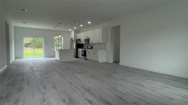 unfurnished living room featuring baseboards, a sink, light wood-style floors, and recessed lighting
