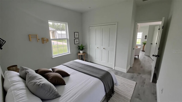 bedroom featuring a closet, light wood-style floors, and baseboards
