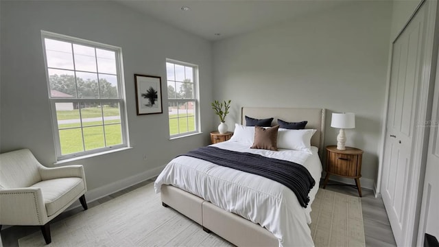 bedroom featuring baseboards, multiple windows, and light wood-style flooring