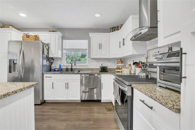 300 Hickory Ct, Apopka, FL 32712 - kitchen with stainless steel appliances, wall chimney range hood, a sink, white cabinetry, and tasteful backsplash