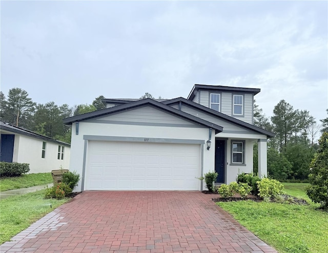 view of front of home with decorative driveway, an attached garage, a front yard, and stucco siding