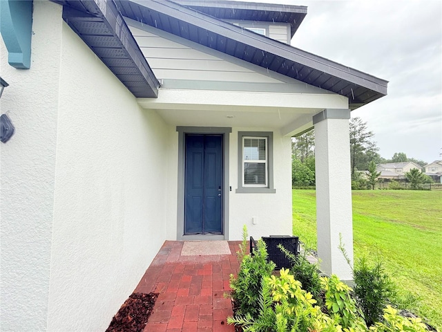 property entrance with a yard, stucco siding, and a porch