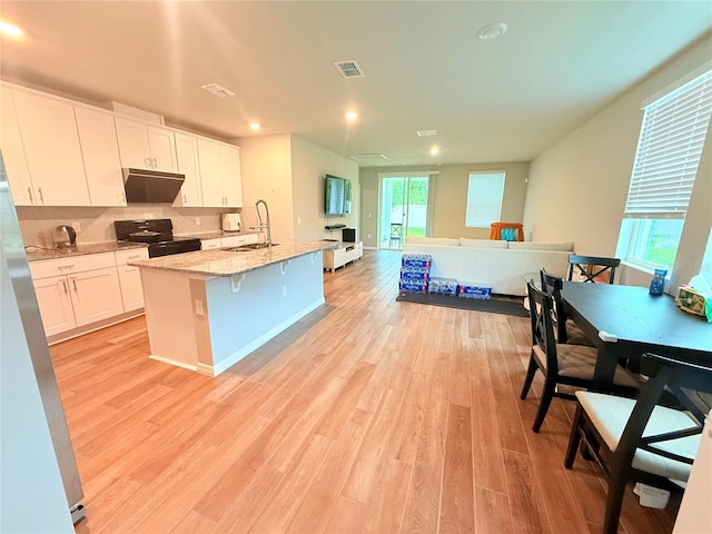 kitchen with black range with electric stovetop, a sink, an island with sink, white cabinets, and recessed lighting