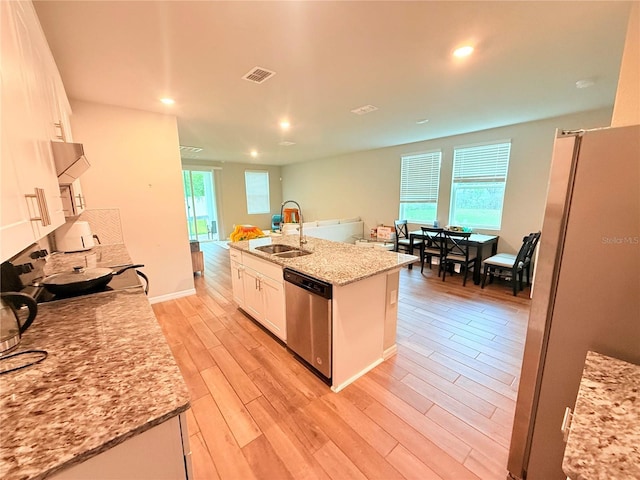kitchen featuring stainless steel appliances, a sink, white cabinets, light wood-style floors, and recessed lighting