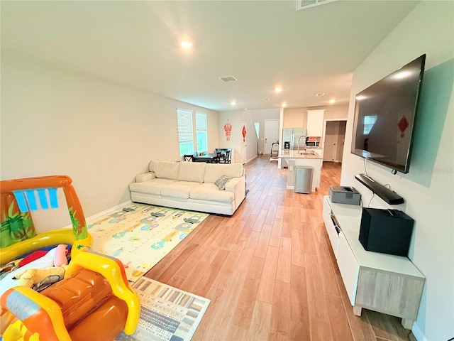 living area with light wood-style flooring, baseboards, and recessed lighting