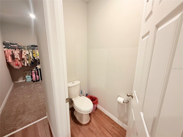 bathroom with toilet, wood finished floors, and baseboards