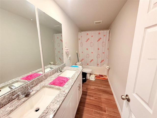 bathroom featuring wood finished floors, toilet, double vanity, shower / tub combo, and baseboards