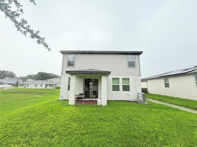 rear view of house with a yard, central AC, and stucco siding
