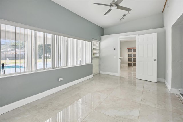 spare room featuring ceiling fan, baseboards, and lofted ceiling