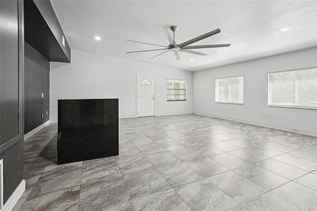 unfurnished living room with a ceiling fan, a textured ceiling, recessed lighting, and baseboards