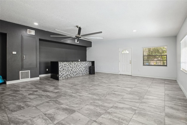 unfurnished living room featuring a ceiling fan, a textured ceiling, baseboards, recessed lighting, and marble look tiles