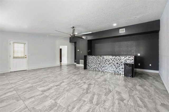 unfurnished living room with a ceiling fan, a textured ceiling, baseboards, and light marble finish floors
