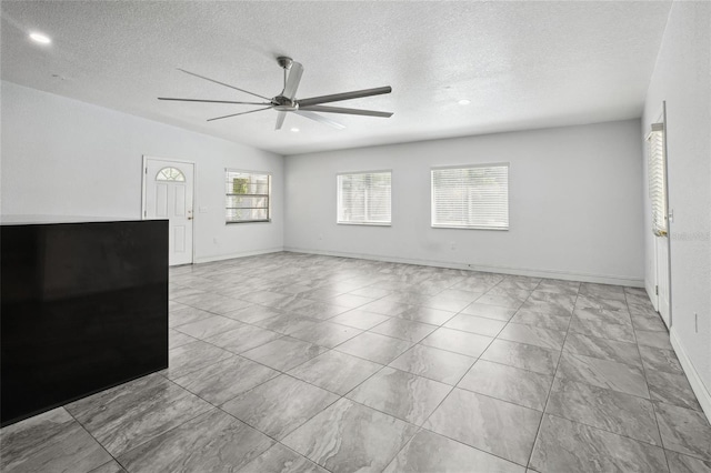 unfurnished living room with a ceiling fan, a textured ceiling, recessed lighting, and baseboards