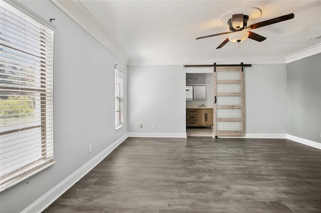 unfurnished living room with a barn door, a ceiling fan, baseboards, crown molding, and dark wood finished floors
