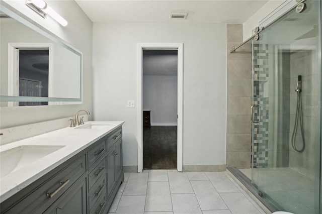 full bathroom featuring a stall shower, tile patterned flooring, double vanity, and baseboards