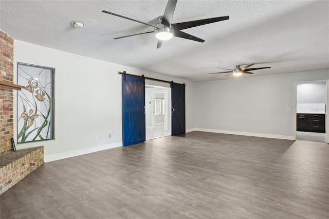 949 Shadow Oaks Rd, Kissimmee, FL 34744 - unfurnished living room with a ceiling fan, a barn door, a textured ceiling, wood finished floors, and a fireplace