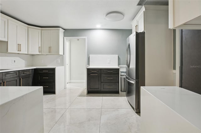 949 Shadow Oaks Rd, Kissimmee, FL 34744 - kitchen with freestanding refrigerator, light stone counters, and white cabinets