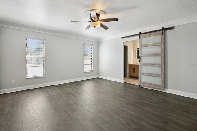 949 Shadow Oaks Rd, Kissimmee, FL 34744 - unfurnished bedroom with a barn door, a textured ceiling, dark wood-style flooring, ornamental molding, and connected bathroom