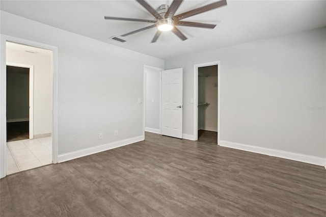 949 Shadow Oaks Rd, Kissimmee, FL 34744 - unfurnished bedroom with dark wood-style floors, a walk in closet, ceiling fan, and connected bathroom