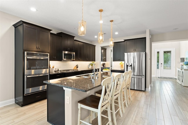 15420 Southern Martin St, Winter Garden, FL 34787 - kitchen featuring appliances with stainless steel finishes, a sink, dark stone countertops, a kitchen bar, and light wood-style flooring