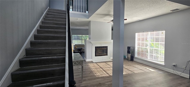 8612 Valley Ridge Ct, Orlando, FL 32818 - stairs featuring baseboards, wood finished floors, a fireplace with flush hearth, a ceiling fan, and a textured ceiling