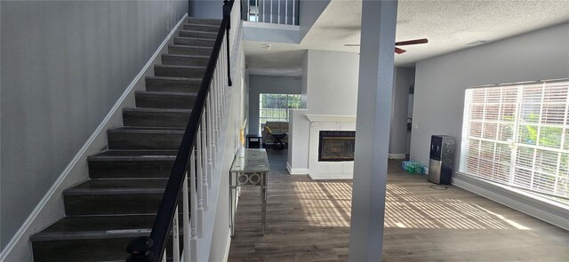 8612 Valley Ridge Ct, Orlando, FL 32818 - stairs featuring wood finished floors, a ceiling fan, baseboards, a multi sided fireplace, and a textured ceiling