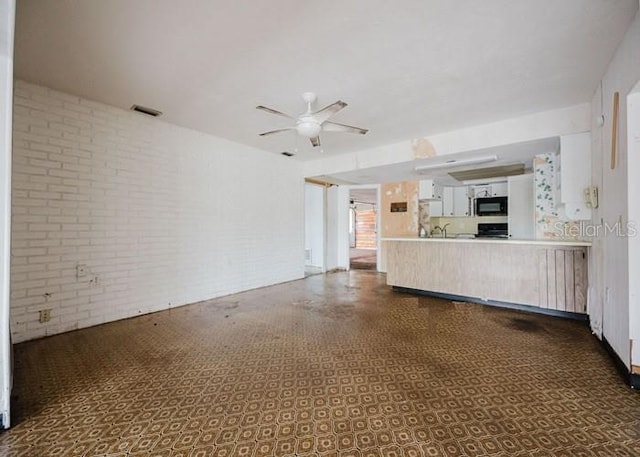 5500 Leeward Ln, New Port Richey, FL 34652 - unfurnished living room featuring brick wall and ceiling fan