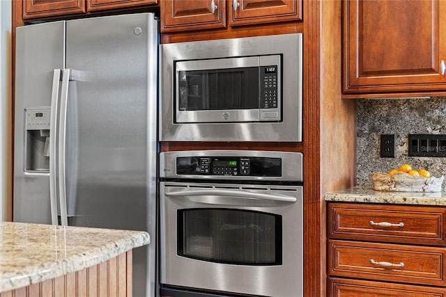 1070 Henley Downs Pl, Lake Mary, FL 32746 - kitchen with appliances with stainless steel finishes, tasteful backsplash, light stone counters, and brown cabinets