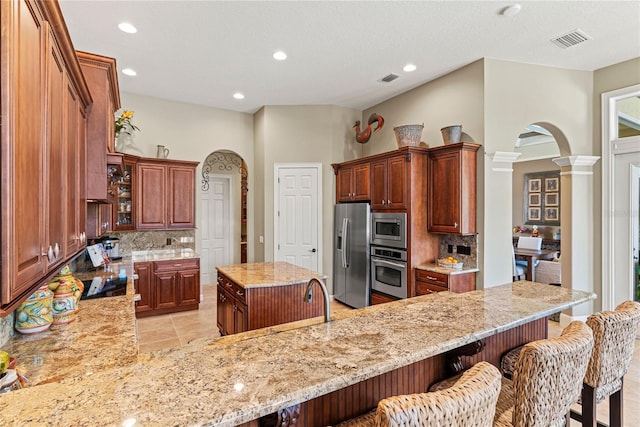 1070 Henley Downs Pl, Lake Mary, FL 32746 - kitchen featuring appliances with stainless steel finishes, arched walkways, decorative columns, tasteful backsplash, and recessed lighting