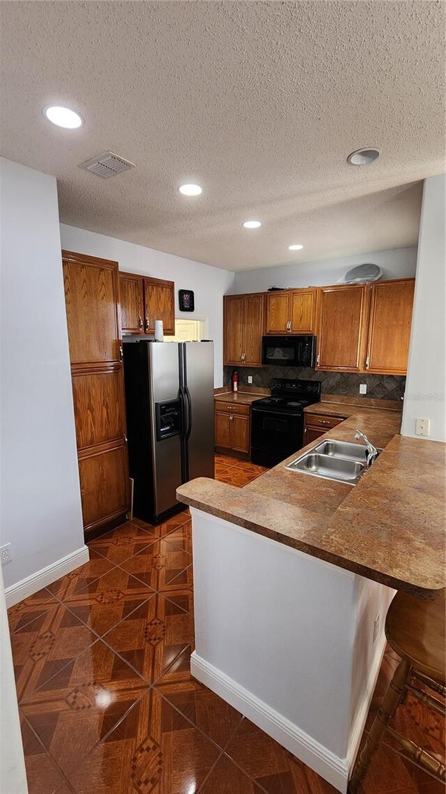 2157 Island Walk Dr, Orlando, FL 32824 - kitchen featuring black appliances, a sink, brown cabinetry, recessed lighting, and a peninsula
