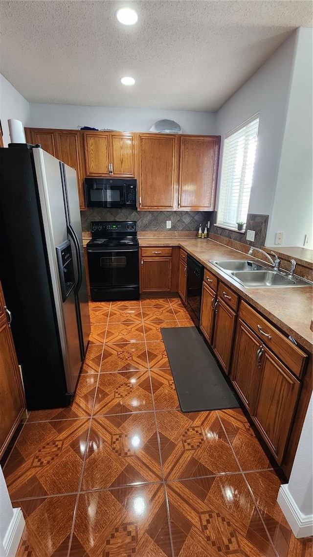 2157 Island Walk Dr, Orlando, FL 32824 - kitchen with black appliances, a sink, a textured ceiling, brown cabinets, and backsplash