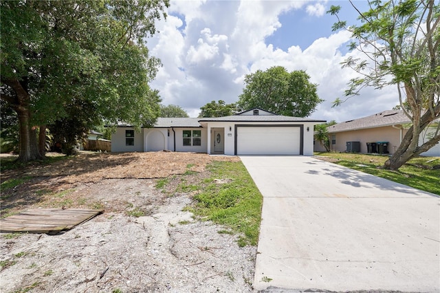 ranch-style house with a garage, concrete driveway, stucco siding, and central AC unit