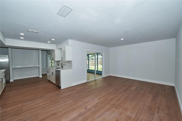 kitchen with a sink, light countertops, wood finished floors, white cabinetry, and recessed lighting