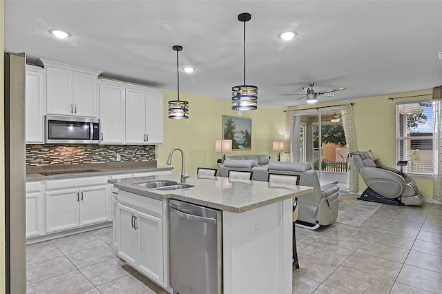 4051 Prairie Reserve Blvd, Orlando, FL 32824 - kitchen featuring appliances with stainless steel finishes, a sink, open floor plan, light tile patterned floors, and decorative backsplash
