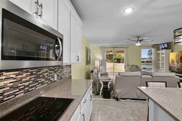 4051 Prairie Reserve Blvd, Orlando, FL 32824 - kitchen featuring stainless steel microwave, black electric cooktop, tasteful backsplash, open floor plan, and a textured ceiling