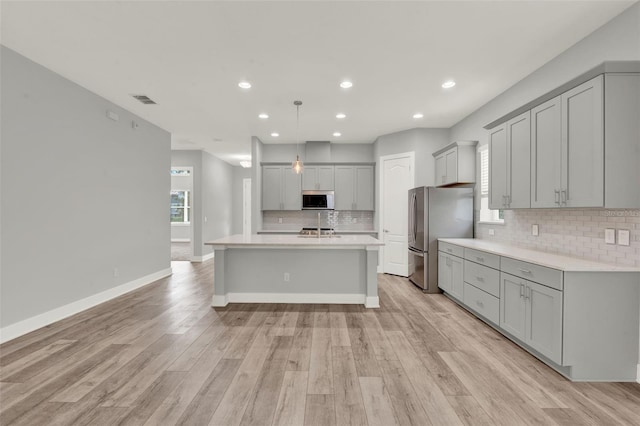 14826 Deaton Aly, Orlando, FL 32827 - kitchen featuring freestanding refrigerator, gray cabinets, light countertops, tasteful backsplash, and light wood-style flooring