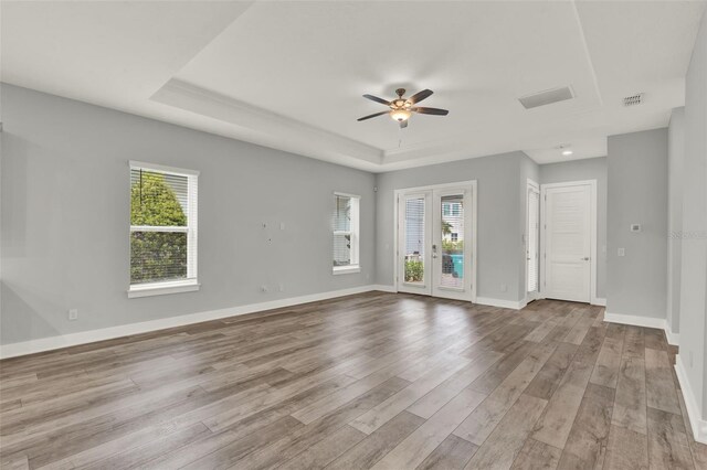 14826 Deaton Aly, Orlando, FL 32827 - unfurnished living room featuring a ceiling fan, plenty of natural light, wood finished floors, and a tray ceiling