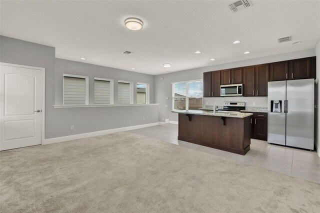 14826 Deaton Aly, Orlando, FL 32827 - kitchen with stainless steel appliances, a breakfast bar area, recessed lighting, dark brown cabinets, and light tile patterned floors