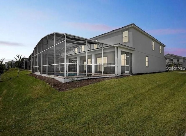 1575 Plunker Dr, Davenport, FL 33896 - back of house at dusk featuring a yard, stucco siding, a pool, and a lanai