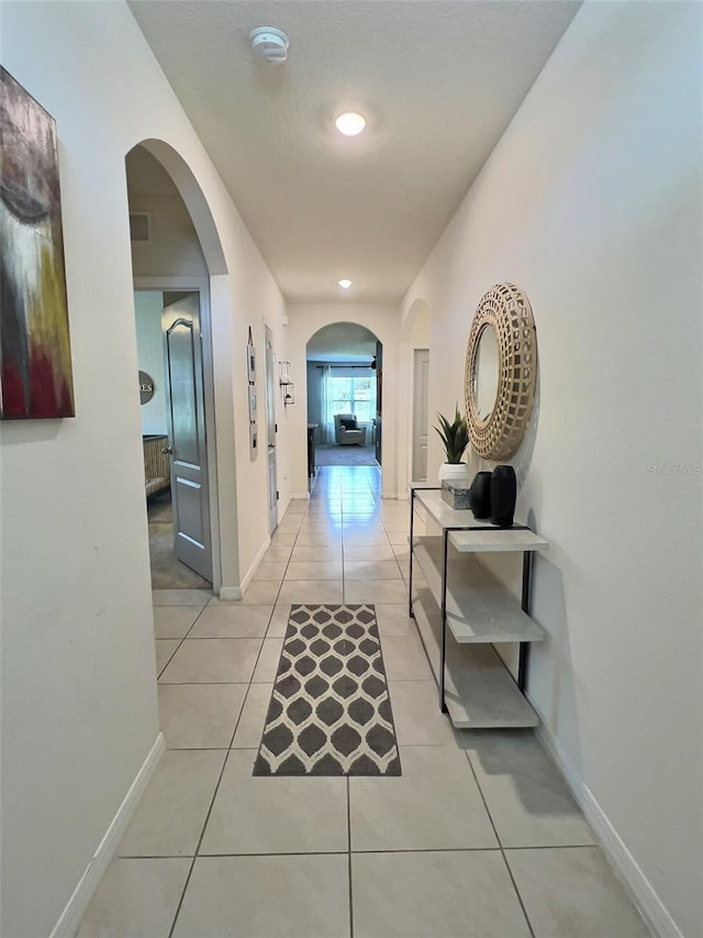 3329 Royal Tern Dr, Winter Haven, FL 33881 - corridor with light tile patterned flooring, baseboards, and arched walkways