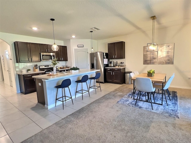 3329 Royal Tern Dr, Winter Haven, FL 33881 - kitchen featuring stainless steel appliances, a breakfast bar, dark brown cabinets, arched walkways, and a textured ceiling