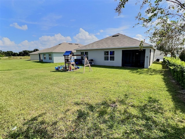 3329 Royal Tern Dr, Winter Haven, FL 33881 - back of house with a playground, a lawn, and stucco siding