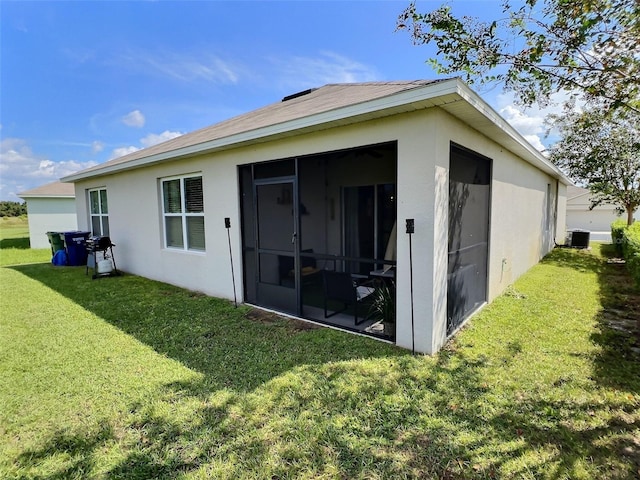 3329 Royal Tern Dr, Winter Haven, FL 33881 - rear view of property featuring a yard, stucco siding, a sunroom, and central air condition unit