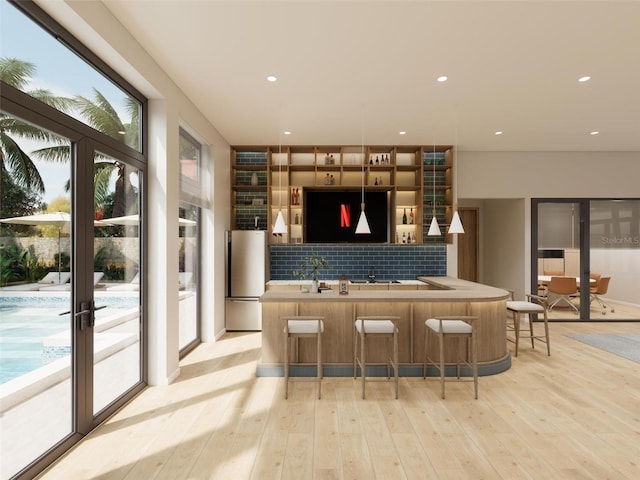 209 Breezeway Dr, Davenport, FL 33897 - indoor wet bar featuring freestanding refrigerator, light wood finished floors, backsplash, and recessed lighting