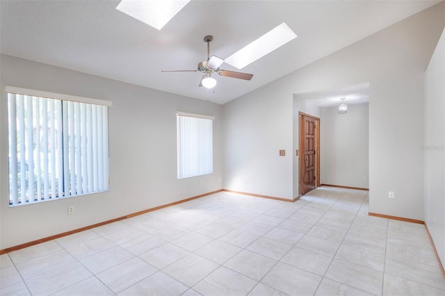 unfurnished room featuring a skylight, vaulted ceiling, a ceiling fan, and baseboards