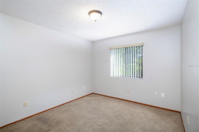 spare room with carpet flooring, baseboards, and a textured ceiling
