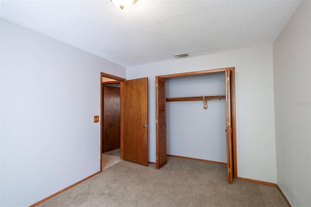 unfurnished bedroom with light carpet, a closet, a textured ceiling, and baseboards